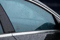 Picture of a wet black car with tinted windows 